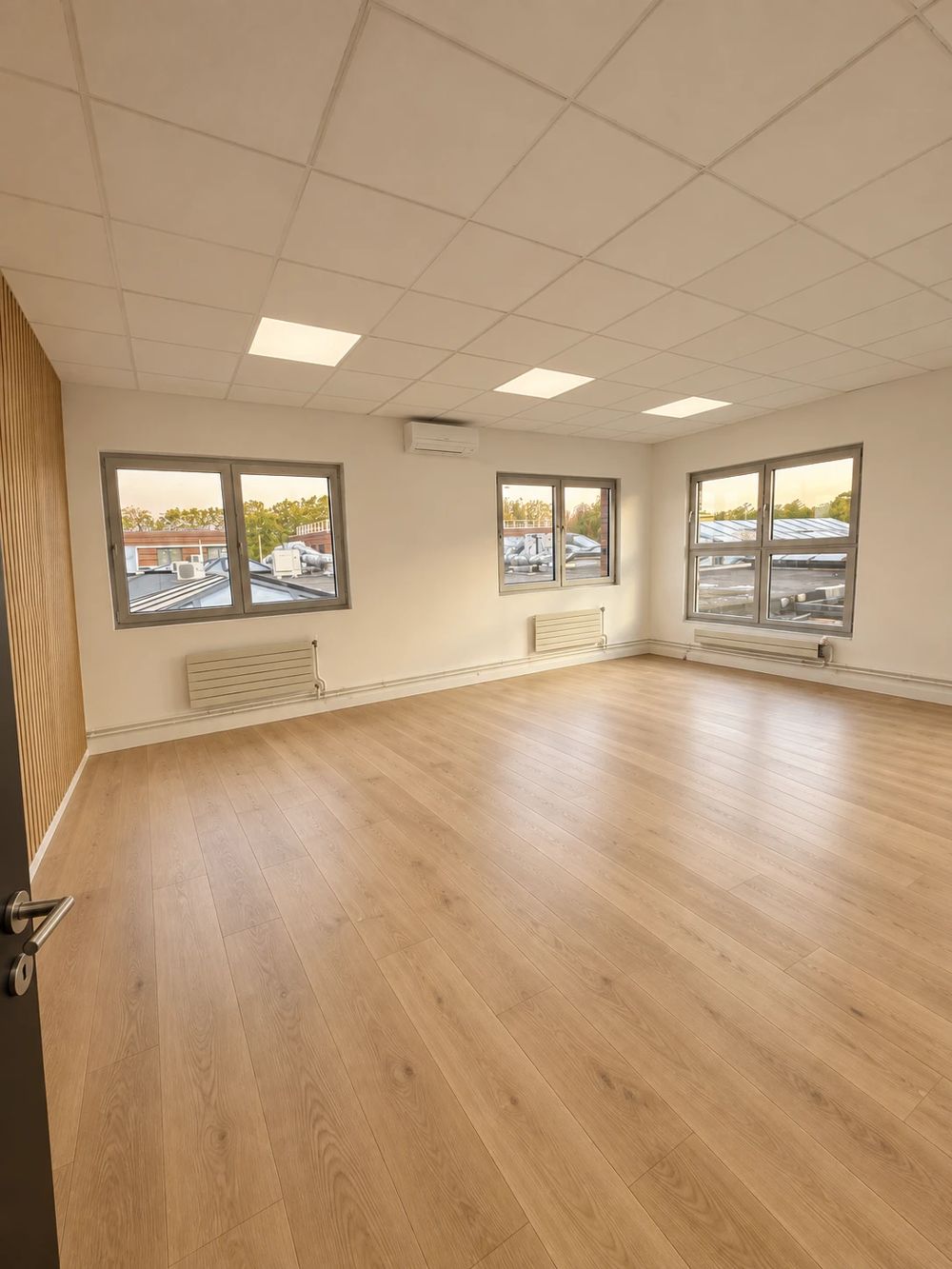 Bureau aux trois fenêtres, climatisé, parquet clair.